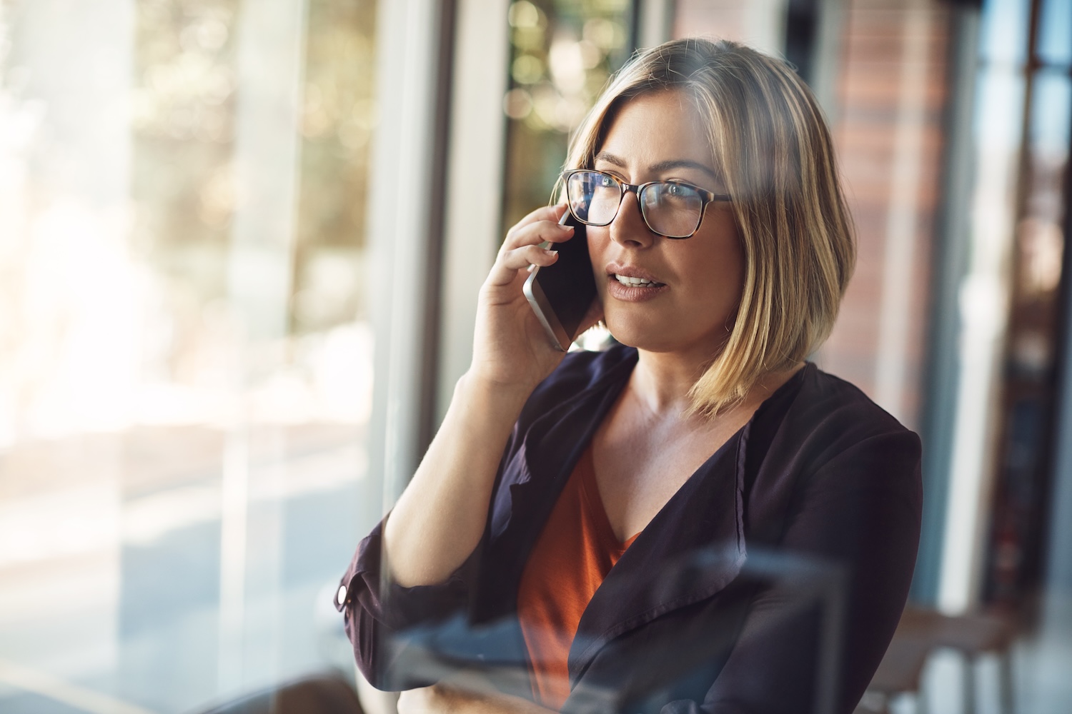 Businesswoman making a mobile phone call to have conversation with management about the company in a modern office. Confident professional blonde female in leadership talking on her smartphone Schedule an appointment at Precision Eye Clinic in Savannah, TN