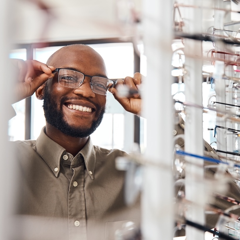 The perfect pair for me. Shot of a young man buying a new pair of glasses at an optometrist store. Comprehensive eye exam evaluating vision and screening for eye disease